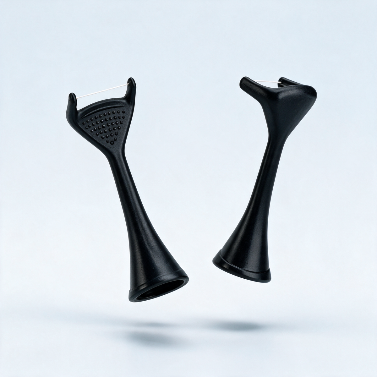 Flossei reusable floss heads in Midnight Black, two heads floating at angles, one showing the tongue-scraper dot texture